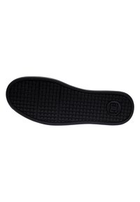 Black rubber shoe sole with textured grip pattern, featuring a logo within a circle and segmented sections for flexibility.