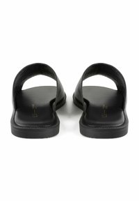 Schwarze Leder-Sandalen mit offenen Zehen und geschwungenen Riemen. Flache Sohlen weisen eine dezente Texturierung und minimalistische Designelemente auf.