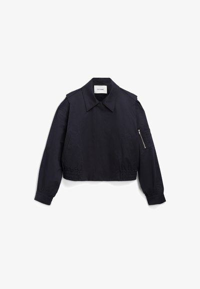 Giacca cropped blu navy con colletto a punta, orlo elasticizzato e maniche lunghe. Presenta tasche laterali e una tasca con zip su una manica.