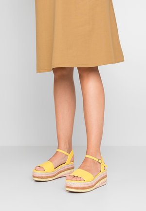 Gele platform sandalen met dikke gevlochten jute zolen en enkelbandjes, met een open teen ontwerp. Gladde matte afwerking.