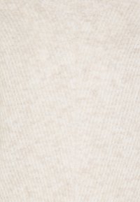 Detalj av mjukt, krämfärgat stickat tyg med ribbad textur och subtilt vertikalt mönster.