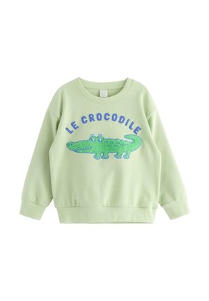 Jasnozielona, dziecięca bluza z długim rękawem z zielonym, kreskówkowym krokodylem i napisem „LE CROCODILE” w kolorze niebieskim nad nim.