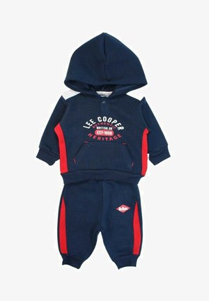 Survêtement bleu marine avec des accents rouges. Comprend un sweat à capuche avec une poche avant et un pantalon assorti avec un petit logo sur la jambe.