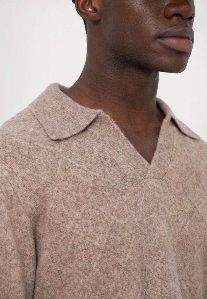 Pull en tricot brun clair avec un motif en losange texturé, doté d'un col en V et fabriqué en un doux mélange de laine fine.