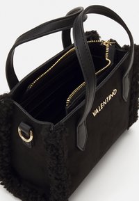 Borsa nera con un lato in texture simile alla pelliccia. Dotata di accessori in oro, chiusura con zip e scomparti interni per l'organizzazione.