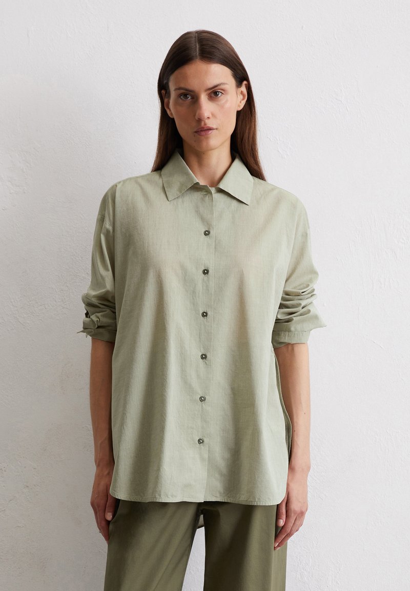 Light green, button-up shirt with a classic collar and rolled sleeves. Made from a soft, textured fabric. Subtle sheen, casual fit.