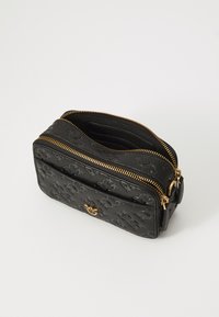 Melnas ādas soma ar reljefa rakstu, diviem rāvējslēdzējiem, zelta krāsas aparatūru, taisnstūra formu un teksturētu virsmu.