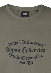 Olivengrøn bomulds T-shirt med rund halsudskæring og marineblå trykt tekst: "Petrol Industries Repair & Service DenimDrivenCo. Est. '89".