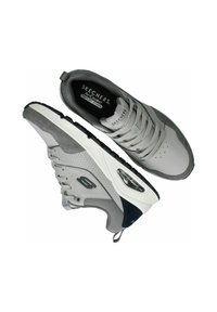Sneaker grigie Skechers con parte superiore in suede testurizzato e mesh, suole imbottite e dettagli di ammortizzazione ad aria visibile. Presentano lacci tondi.