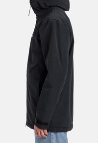 Czarna kurtka z kapturem o prostym kroju, z zapięciem na zamek na przodzie, mankietami na rzepy i bocznymi kieszeniami. Wykonana z gładkiego, wytrzymałego materiału.