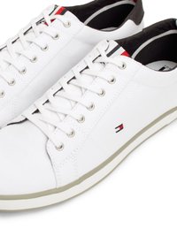 Sneaker in tela bianca con design a lacci con asole, accenti neri e rossi in contrasto, suola in gomma grigia e logo sul lato.
