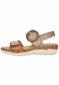 Sandale en cuir marron avec une semelle en liège, une sangle texturée dorée et un détail d'accent circulaire. Design ouvert à l'avant avec sangle de cheville réglable.