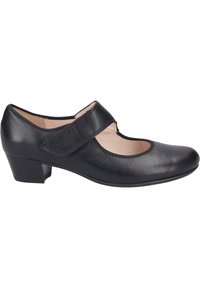 Chaussure Mary Jane en cuir noir avec un bout arrondi, une sangle à boucle adhésive et un petit talon bloc. Texture lisse avec un design découpé.
