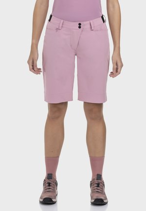 Hellrosa kniehohe Shorts mit schmaler Passform, zwei Fronttaschen und schwarzer Hardware. Kombiniert mit rosa Socken und Wanderschuhen.