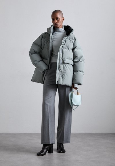 Puffy light gray jacket with a hood, gray fitted top, gray wide-leg trousers, black heeled boots, and a small light blue handbag.