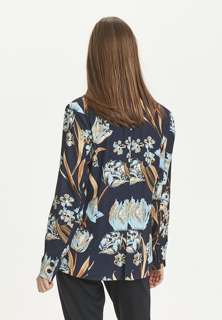 Blouse à manches longues bleu marine avec un motif floral aux tons bleus et bruns, confectionnée en tissu léger avec une coupe décontractée.