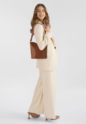 Borsa tote in pelle marrone con texture liscia, forma rettangolare e tracolla regolabile, esposta su uno sfondo neutro.