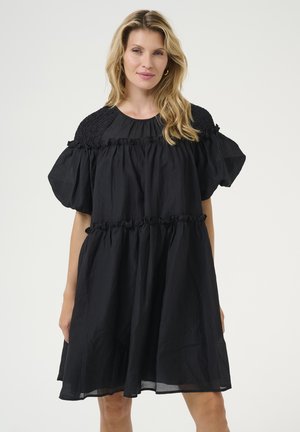 Schwarzes Kleid mit lockerem Schnitt, featuring Puffärmel, gerafftem Oberteil und Rüschendetails. Aus leichtem Stoff mit subtiler Textur gefertigt.