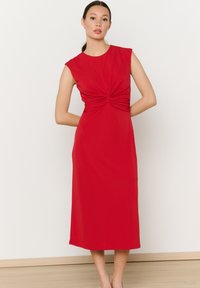 Vestido midi rojo con mangas cortas, presenta un drapeado frontal retorcido. Hecho de una tela suave, llega hasta medio pantorrilla, mostrando una silueta elegante.