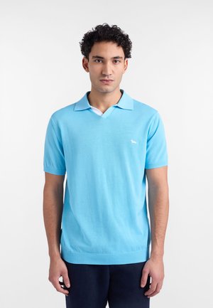 Svjetloplava polo majica kratkih rukava s V-izrezom, s bijelim ovratnikom i malim bijelim logotipom na lijevoj strani grudnog koša. Glatka tekstura.