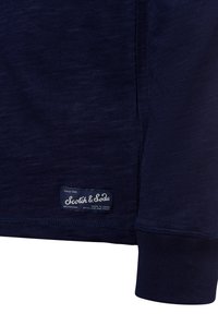 Navy blue long-sleeve shirt made of textured fabric features a rounded neckline, cuffed sleeves, and a branded label at the hem.