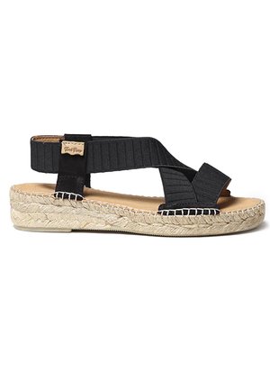 Sandale espadrille noire avec des sangles élastiques épaisses, une semelle intermédiaire en jute tissé et une semelle intérieure rembourrée pour le confort. Ajout de texture avec un bord cousu.