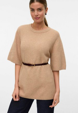 Suéter de punto beige oversized con mangas cortas, cuello acanalado y un cinturón de cuero marrón. Textura suave y corte relajado, combinado con jeans oscuros.
