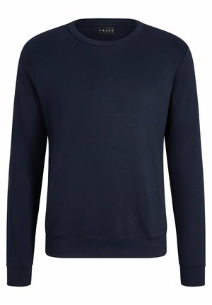 Granatowa bluza z długim rękawem i okrągłym dekoltem, połączona z jasnoszarymi zwężającymi się dresami oraz czarnymi sneakersami. Swobodny zestaw odzieży sportowej.