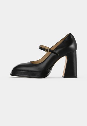 Chaussure Mary Jane noire en cuir, avec une bride à la cheville, une boucle dorée, une semelle plateforme et un talon haut épais.