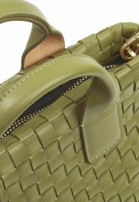 Borsa a tracolla in pelle verde intrecciata con doppi manici, superficie testurizzata, chiusura con zip e dettagli in metallo dorato.