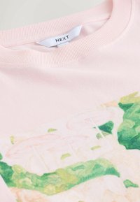 Svetlo rožnata bombažna majica s kratkimi rokavi, na sprednji strani z barvitim potiskom roza dežnikov in zelenja.