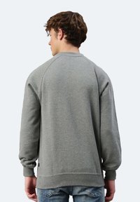 Felpa grigia a maniche lunghe con scollatura a girocollo e maniche raglan. Presenta un tessuto texturizzato e polsini a coste sull'orlo.