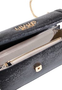 Borsa in pelle nera testurizzata con logo dorato, tracolla a catena e tasche interne con cerniera. Presenta una chiusura con ferratura dorata.