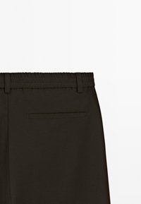 Sorte bukser med elastisk talje og bæltestropper samt en enkelt vandret baglomme på højre side.