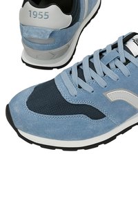 Sneaker in suede azzurro chiaro con pannelli in mesh, dotata di accenti blu scuro, tallone grigio, suola texture e dettagli evidenti "1955" sulla parte posteriore.