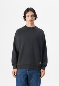 Svart crewneck sweatshirt med lange ermer, ribbet kant og mansjetter, laget av myk stoff; har et lite logo-merke nederst.