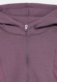 Μωβ ζακέτα με φερμουάρ, κατασκευασμένη από απαλό ύφασμα με υφή, με ψηλό γιακά και μεταλλικό φερμουάρ, σχεδιασμένη για άνεση και ευελιξία.