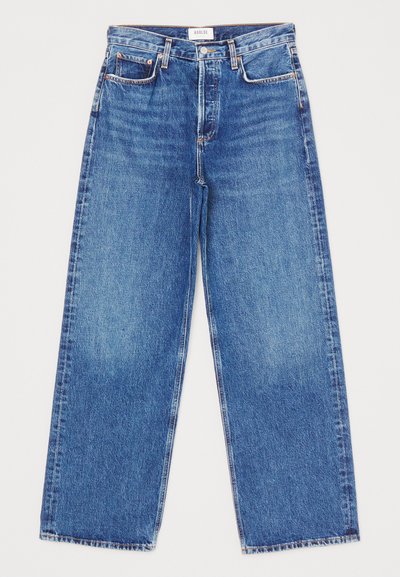 Jean large en denim de lavage bleu moyen avec cinq poches, jambes droites et détails de surpiqûre. Étiquette de marque visible à la taille.
