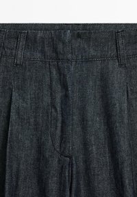 Dark denim trousers with a smooth texture, featuring flat pleats, a standard waistband, and no visible hardware or embellishments.