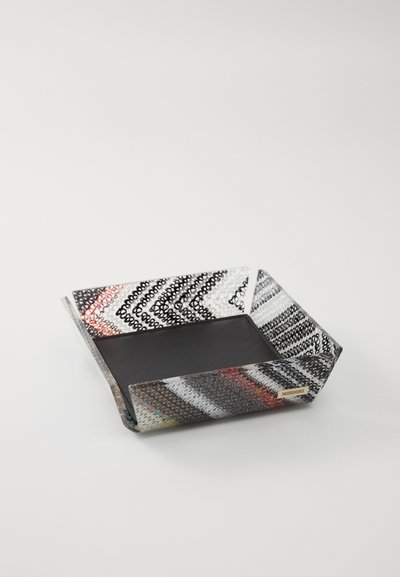 Plateau hexagonal avec une surface texturée à motifs multicolores et un intérieur noir mat. Les bords sont légèrement surélevés. Étiquette de marque en métal visible.