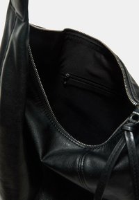 Schwarze Ledertasche mit Reißverschluss, mit einer glatten Textur und einem Innenfach mit einem Reißverschlussfach.