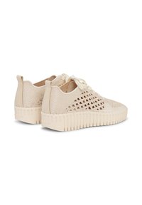Beige gebreide sneakers met geperforeerde mesh-zijkanten, dikke geribbelde zolen, trek-lussen bij de hielen en crème kleurige veters, weergegeven vanaf de achterkant en zijkant.