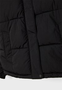 Giubbotto bomber nero con sezioni trapuntate, chiusura con zip e tasca laterale. Il tessuto ha una texture liscia con una finitura opaca.