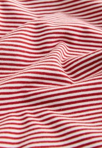 Tissu rayé horizontal rouge et blanc avec des plis doux et une texture tricotée visible.