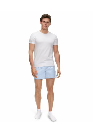 T-shirt blanc à manches courtes associé à un short rayé bleu clair, complété par des chaussettes blanches. Accent sur un ajustement et un design décontractés et confortables.