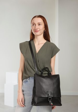 Zwarte leren rugzak met een gestructureerde vorm, voorflapsluiting en een bovenste handvat. Voorzien van een verstelbare schouderband en een kleurrijk label.