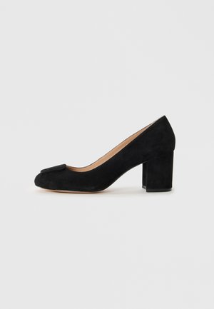 Décolleté in suede nero con punta tonda e un dettaglio a fiocco decorativo sulla parte anteriore. Tacco a blocco per stabilità. Fodera interna liscia.