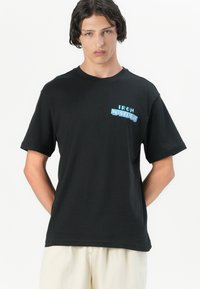 Sort bomulds t-shirt med et multicolor grafisk logo, der står "IRON MAIDEN" på brystet. Kortærmet og en afslappet pasform.