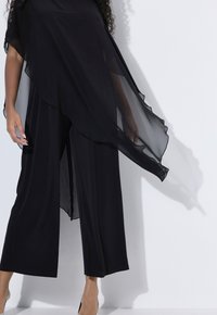 Mono negro con piernas anchas, capas de superposición transparente que caen, textura suave, diseño sutil y una silueta elegante.