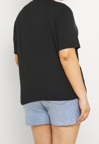 Sort kortærmet t-shirt med en afslappet pasform, parret med lyseblå denimshorts med en frayed hem. 100% bomuldsmateriale, afslappet design.